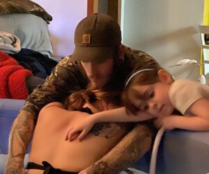A man and two children sleeping on the bed.