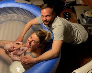 A man and woman in a tub with baby.