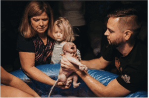 A man and woman holding a baby in front of two women.