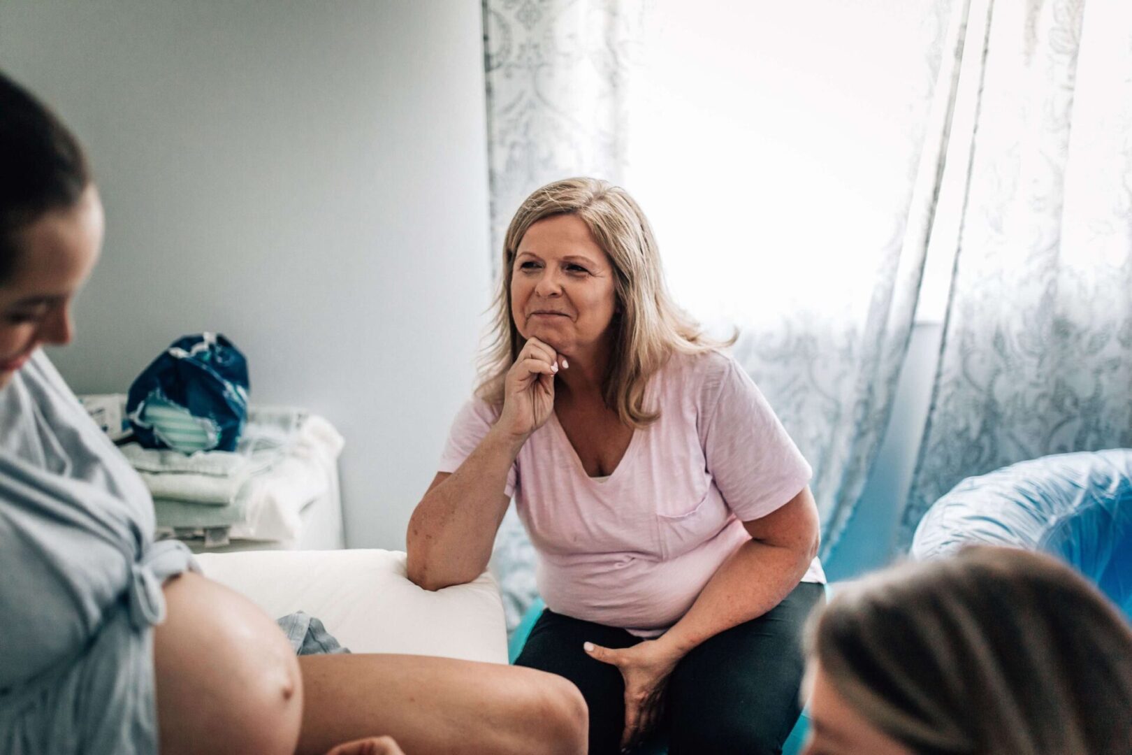 Woman supporting pregnant person in home setting.